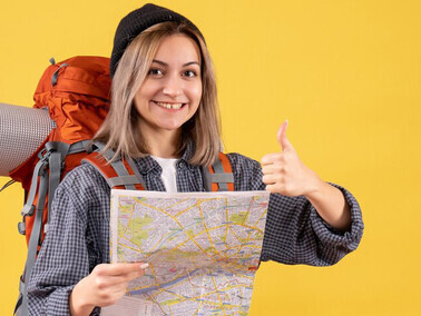 Front view of a female traveler with a backpack, holding a map and exploring her destination