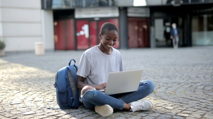 Estudante sentada com computador na rua