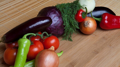 A vibrant medley of tomatoes, peppers, onions, and eggplants adorns the chopping board, evoking the rich tapestry of Turkish cuisine