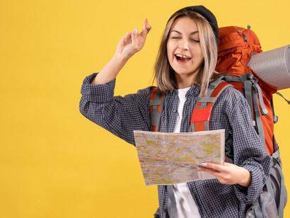 Young female traveler with a backpack, holding a map and planning her route while exploring a new location