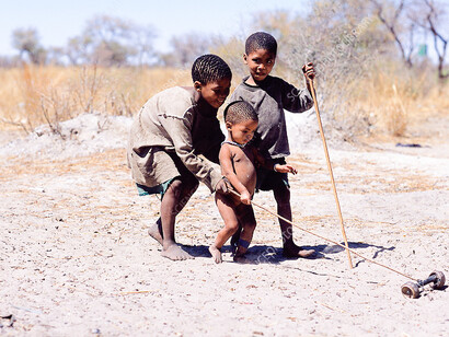 Namibian kids playing in the sand barefoot with sticks
