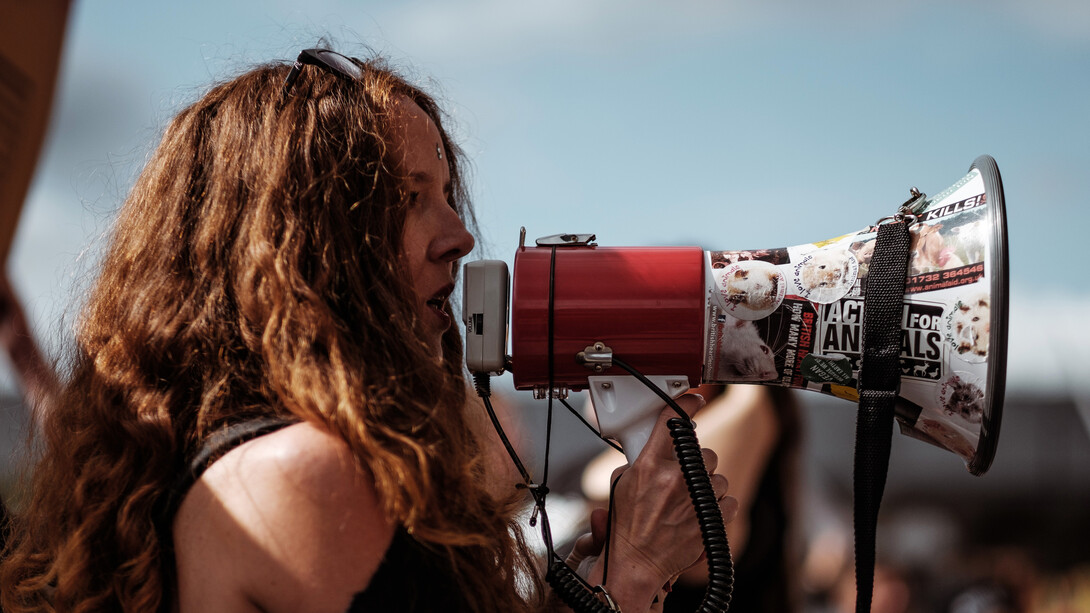 Mujer utiliza un altoparlante en una manifestación en Londres, Reino Unido. Comunicar es controlar sin usar la fuerza física, sino con el uso de palabras, gestos y postura