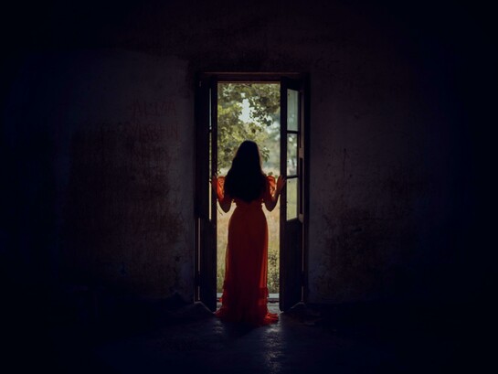Standing at the threshold between darkness and light, she pauses in the stillness of becoming