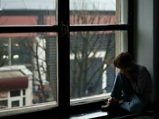 A child sitting isolated and motionless, reflecting the quiet grief of a boy who still waits to be found