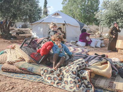 Amidst the hardships of the Idlib Governorate in Syria, poignant images unfold as children sit together in a refugee camp