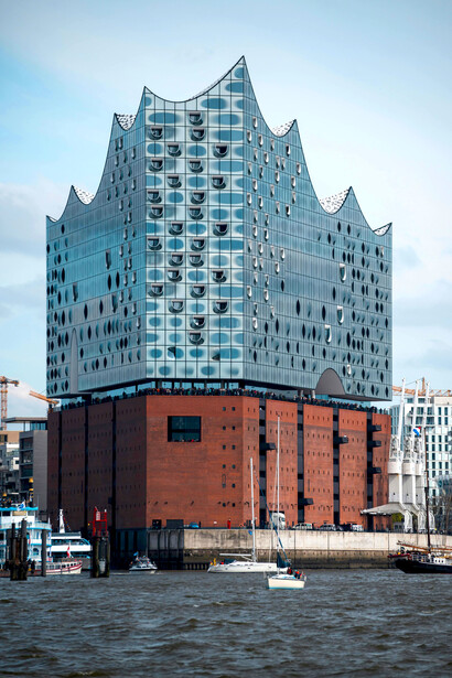 Situated in northern Germany’s port city of Hamburg, on the Grasbrook peninsula of the Elbe River, the Elbphilharmonie (Elphi) captivates with its glass structure shaped like a wave or iceberg, resting atop a historic brick warehouse in the HafenCity district near the Speicherstadt