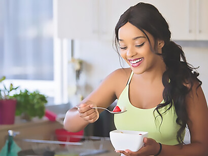 A woman exuding positivity, wearing a smile as she joyfully prepares a nutritious and health-conscious meal