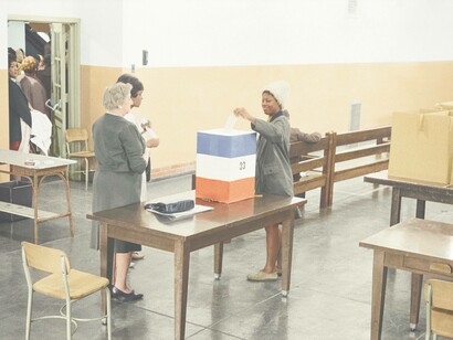 An enthusiastic voter submitting their ballot in the box and soon becoming a statistic in a polling result