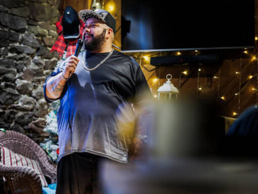 A Latino comedian entertains the audience with a stand-up act at a private country club