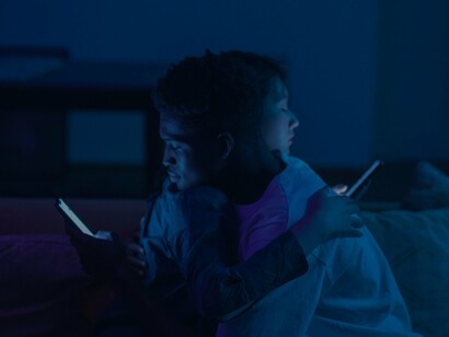 Two people hugging whilst looking at mobile phones