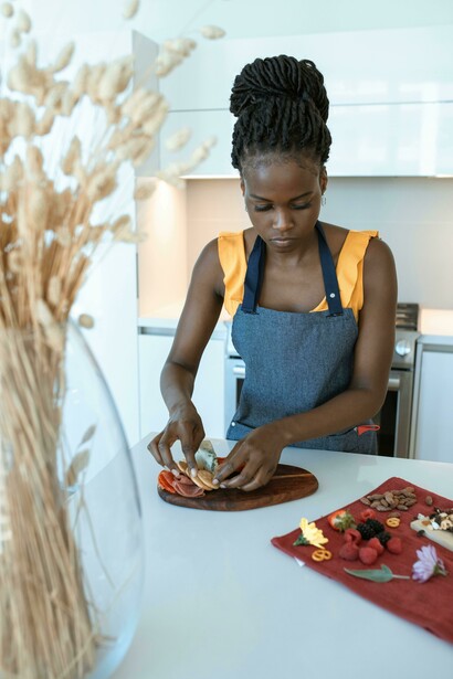 Woman placing sliced strawberries neatly on a wooden plate