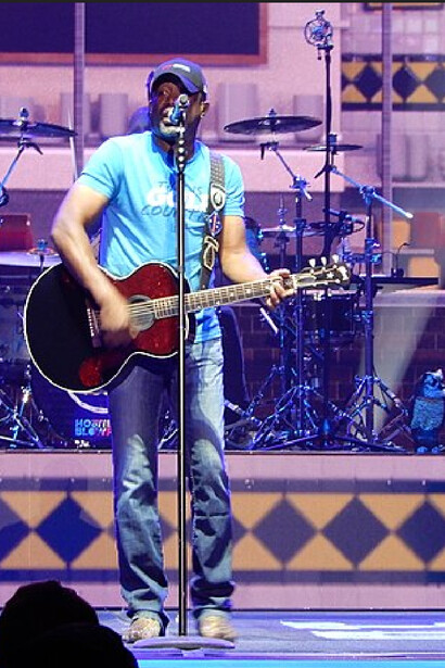 Framed by drumheads and neon tones Darius Rucker plays his guitar with enthusiasm  at Madison Square Garden, New York City, New York
