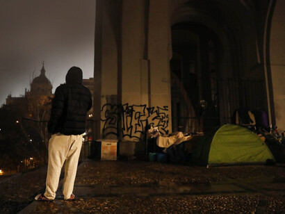 Un joven sin hogar mira el paisaje de Madrid junto a la tienda de campaña donde pasará la noche. Fotografía: Luis Sevillano