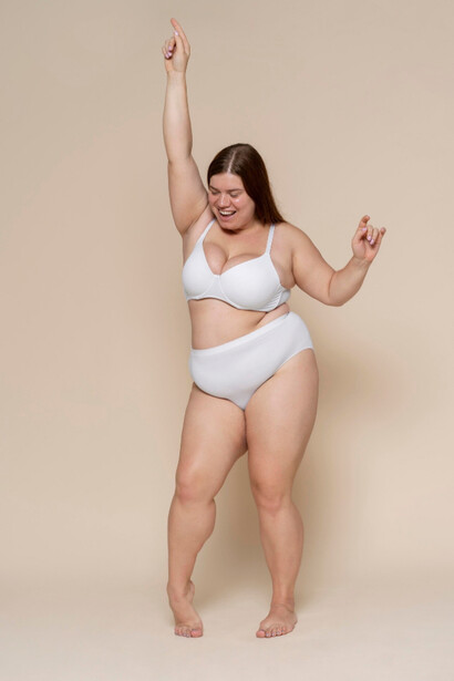 A plus size model in a cheerful mood embracing every part of her body in boldness

