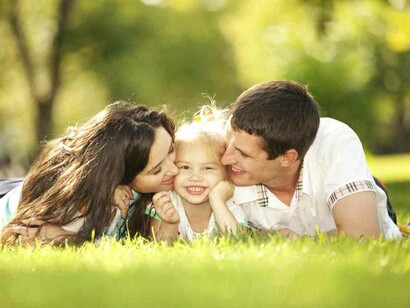Un padre y una madre besan a su hija