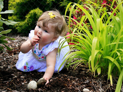 Una niña juega en el suelo y se lleva las manos a la boca