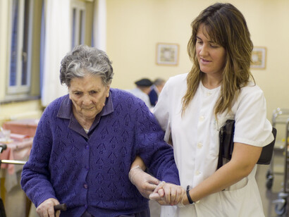 Una cuidadora, paseando junto a una anciana