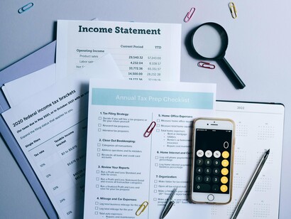 Tax forms and calculator arranged on a table, symbolising the balance between income and obligation