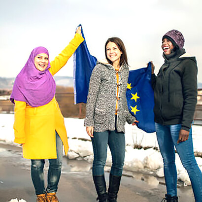 Women of diverse ethnic backgrounds standing together, symbolizing European unity and community, with the EU flag in the background