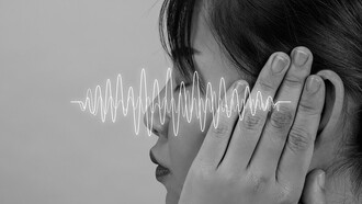 A woman surrounded by sound frequencies, exploring the connection between language and speech sounds