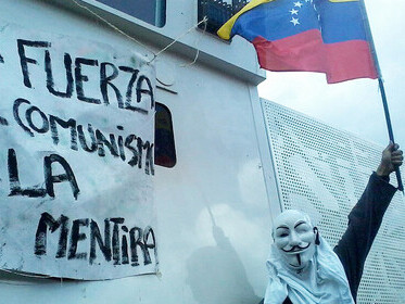 A protester wearing an Anonymous mask while raising a Venezuelan flag during a demonstration in Venezuela