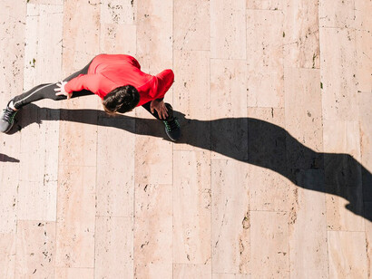A man wearing red joggers, his shadow cast from above
