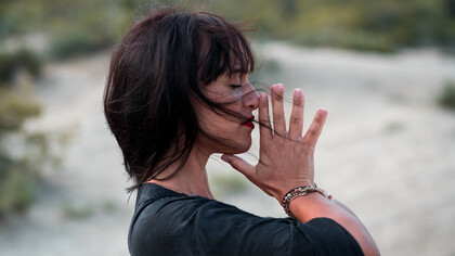 Mulher meditando enquanto brisa assopra seus cabelos