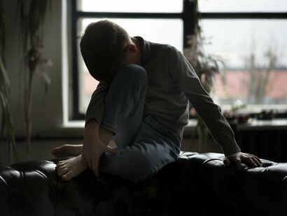 A withdrawn child surrounded by emptiness, conveying the stillness of a life caught in shadow