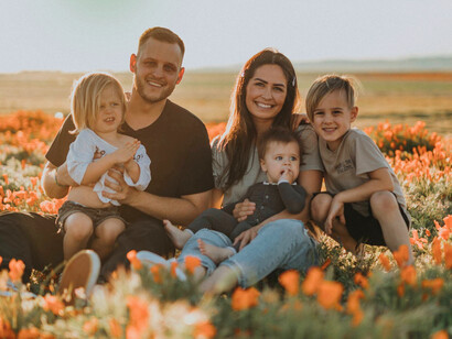 Mother and father sitting in the flowers with their three children