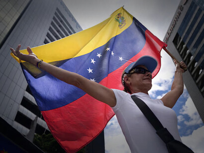 A woman holding a Venezuelan flag amidst skyscrappers in the center of Caracas