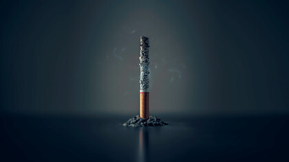A lone cigarette, standing tall with its ash clinging, epitomizing a moment frozen in time