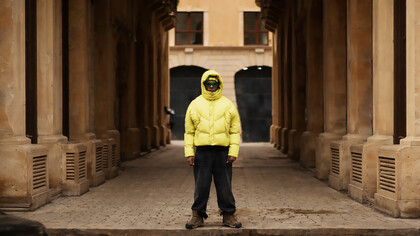 A young man wearing an oversized puffer jacket and wide-leg pants, embracing a trendy look