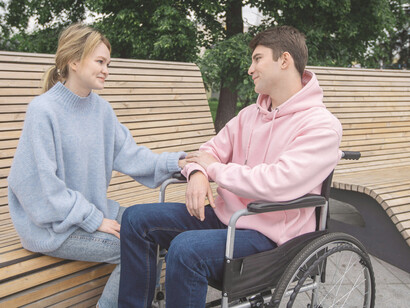 A couple having a conversation in the park, with a man in a wheelchair talking to a woman