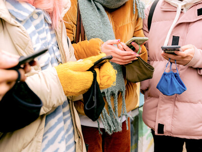 Varias personas consultan sus teléfonos móviles mientras esperan o se desplazan