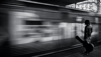 Hombre con una guitarra espera un tren en la estación de Puerto Alegre, Brasil
