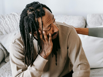 A man with dreadlocks sitting down, in conversation