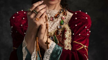 In a crimson velvet gown adorned with pearls and jewels, this figure illustrates how queens used opulent attire and accessories to shape enduring fashion trends