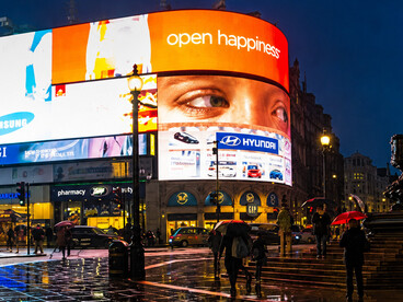 The famous illuminated billboards of Piccadilly Circus light up the crowds surrounding the iconic Eros statue in central London, UK