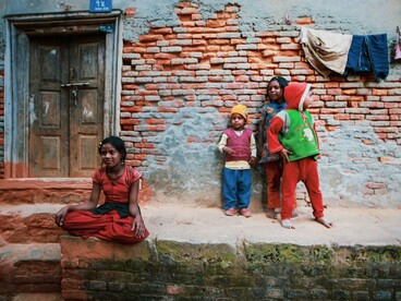 Young children standing before a modest home, symbolizing the communities most affected by unequal access to opportunity and resources