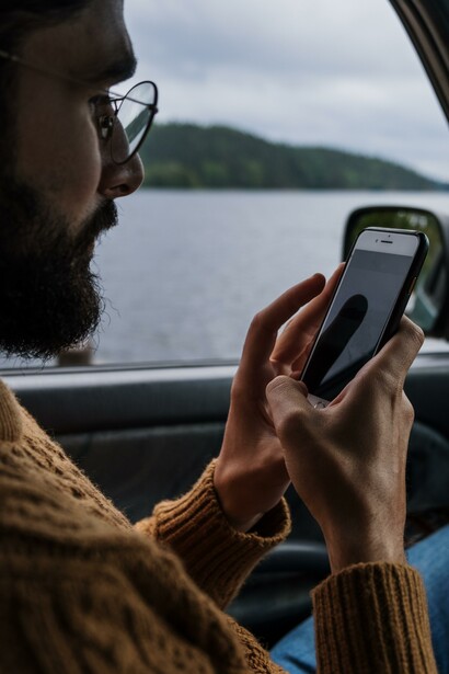 A man looking at the screen of his smartphone while in a car. In Brazil according to a report published in The Guardian, WhatsApp got blocked across the entire country following a court order on Wednesday, December 16, 2015, to all mobile phone internet service providers issued to last for 48 hours