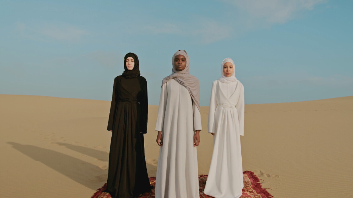 Three women stand resilient in the vast desert, embodying the spirit of Ahlam Mosteghanemi's literary exploration of identity and empowerment in the Arab world