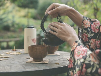A woman pouring tea into her cup in a garden