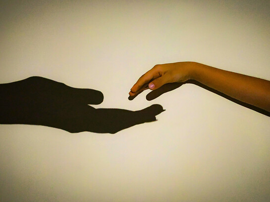 Entre ombres et lumières, attachement et liberté, deux mains cherchent leur juste distance