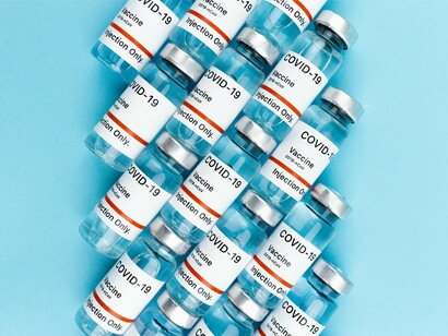 A cluster of COVID-19 vaccine vials, representing the global debate between medical survival and public trust