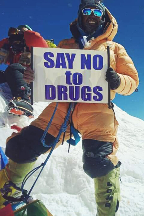 Wangda Sherpa displaying his "Say No to Drugs" campaign buzzwords on top of Everest