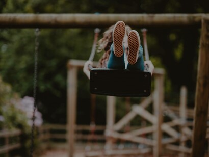 A young person riding the swing so high up that when they come down they might have an energy-shifting effect