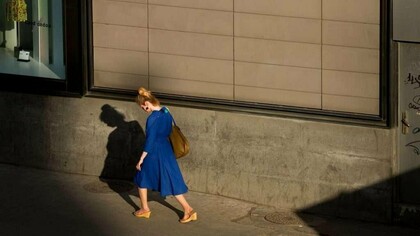 Uma mulher caminha sob a luz do fim do dia, acompanhada pela própria sombra. Entre aquilo que se revela e aquilo que permanece oculto, a felicidade também pode carregar suas contradições