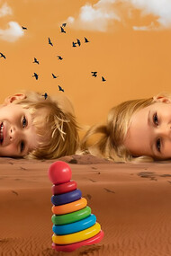 Two happy, independent children lying on the sand under a beautiful sky with clouds