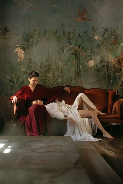 A woman dressed in white with her head on a woman dressed in red's lap