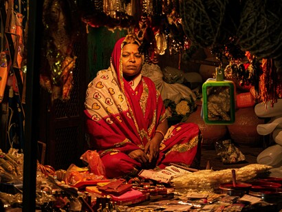A woman wearing traditional clothing and bracelets sits at a bustling bazaar in Hyderabad, Telangana, India